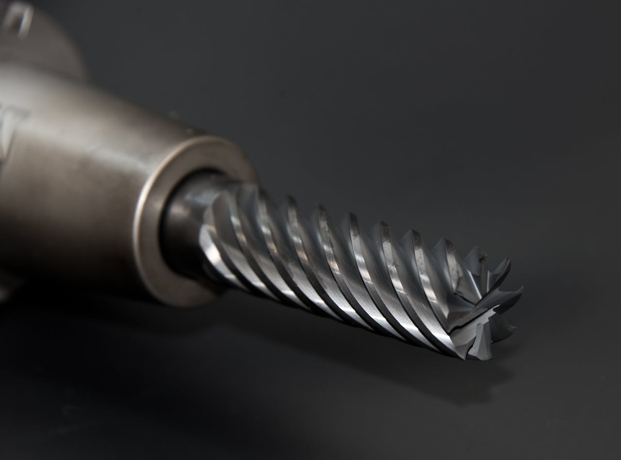 High-quality close-up of a spiral drill bit showcasing metal textures on a black background.